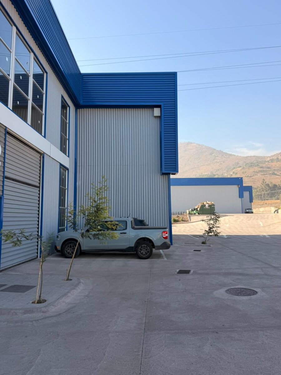Nave industrial con patio pavimentado y cerros de fondo