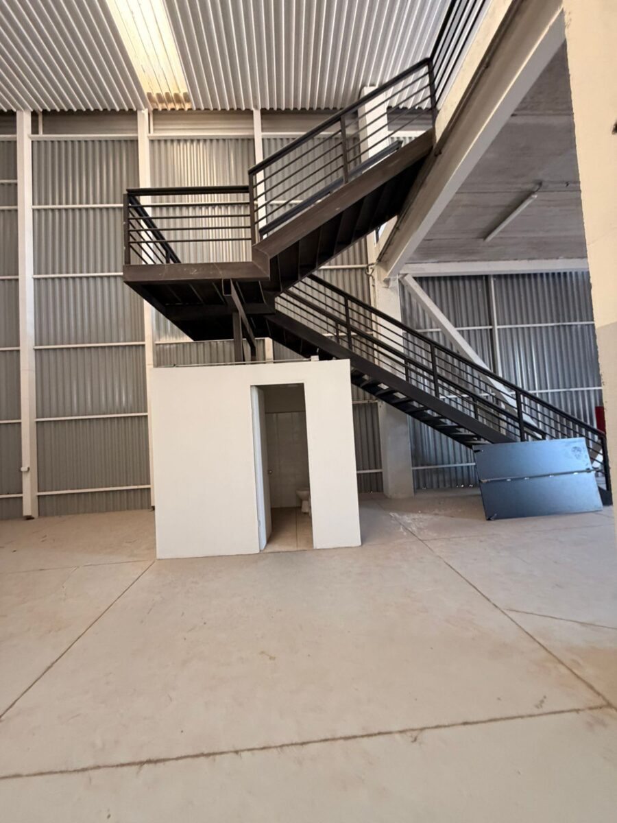 Interior de una bodega con escalera de acero al altillo de oficinas